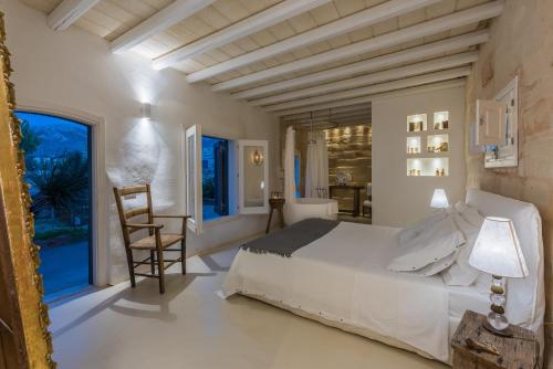 una camera con letto bianco e tavolo e sedie di Dimora Cala del Pozzo a Favignana