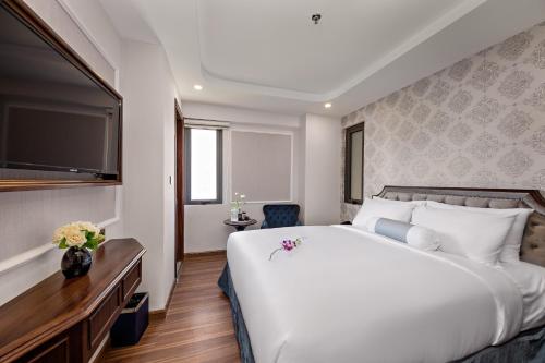 a bedroom with a large white bed and a television at Halina Hotel and Apartment in Da Nang