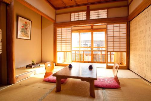 een kamer met een tafel en stoelen en een raam bij Atarashiya Ryokan in Tenkawa