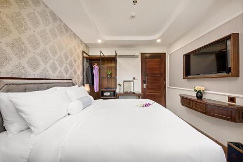 a bedroom with a large white bed and a flat screen tv at Halina Hotel and Apartment in Da Nang