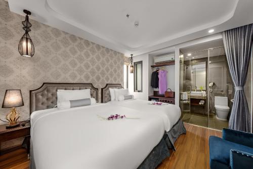a bedroom with a large white bed and a bathroom at Halina Hotel and Apartment in Da Nang