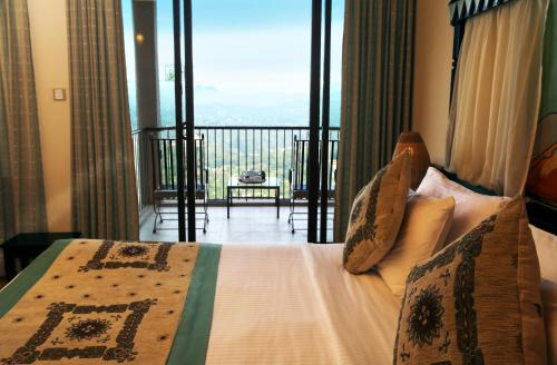 a bedroom with a bed with a view of a balcony at Randholee Resort & Spa in Kandy