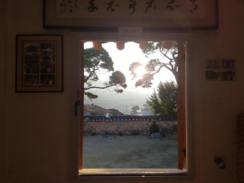a door with a view of a yard through a window at Jukheon Traditional House in Andong