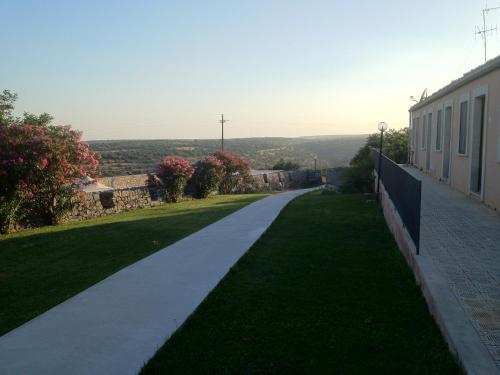 a walkway next to a building with a green lawn at Villa Principe Di Belmonte in Ispica
