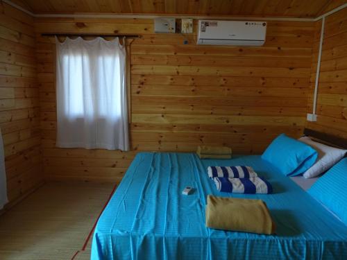 a bedroom with a blue bed in a log cabin at Agonda Paradise in Agonda
