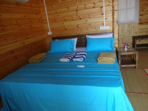 a blue bed in a room with wooden walls at Agonda Paradise in Agonda