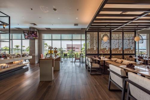 a restaurant with tables and chairs and windows at Enso Hotel in Cikarang