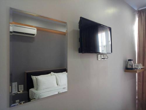 a mirror in a room with a bed and a fan at Sunset Villa Inn in Pantai Cenang