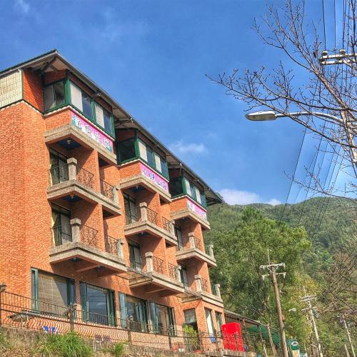 a red brick building with balconies on the side of it at Xanadu Hostel in Yisheng