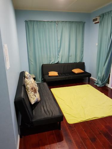 a living room with a black couch and a yellow rug at Azrien Homestay Kundasang in Kampong Kundassan