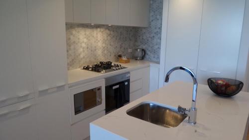 a white kitchen with a sink and a stove at Whitehorse Towers Self Service Holiday Apartment in Box Hill