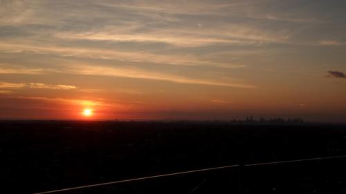 a sunset over a field with a city in the distance at Whitehorse Towers Self Service Holiday Apartment in Box Hill