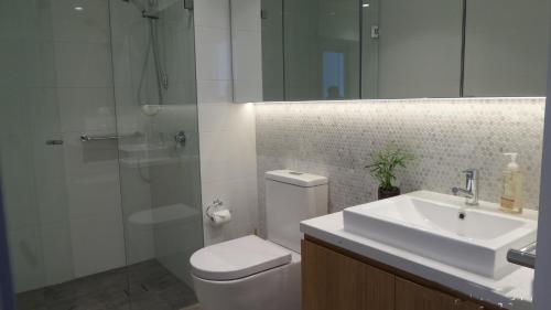 a bathroom with a toilet and a sink and a shower at Whitehorse Towers Self Service Holiday Apartment in Box Hill