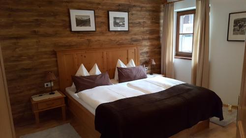 - une chambre avec un grand lit et un mur en bois dans l'établissement Andreas Apartment im Landhaus Moser, à Alpbach