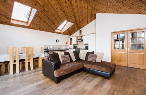 a living room with a couch and a kitchen at Lodge 9 Glengoulandie Lodges in Aberfeldy