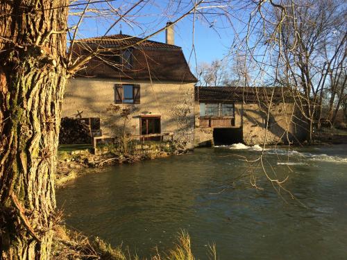 a house next to a river next to a building at LOGIS Hôtel Le Chantoiseau in Chaumont-sur-Aire