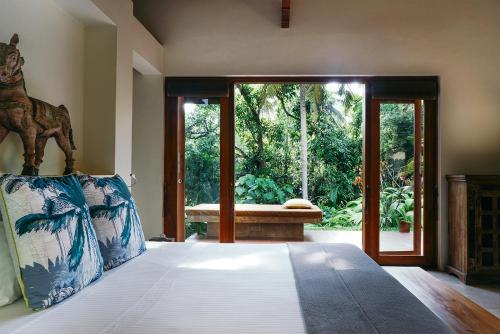 1 dormitorio con 1 cama y puerta de cristal grande en Kumara Luxury Villa, en Weligama