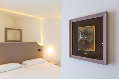 a bedroom with a bed and a painting on the wall at Hotel Al Campanile - Luxury Suites & Apartments in Baveno