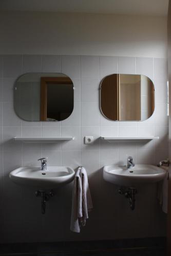 two sinks in a bathroom with mirrors and towels at Panorama Restaurant Sterzingerhaus 1.930m in Vipiteno