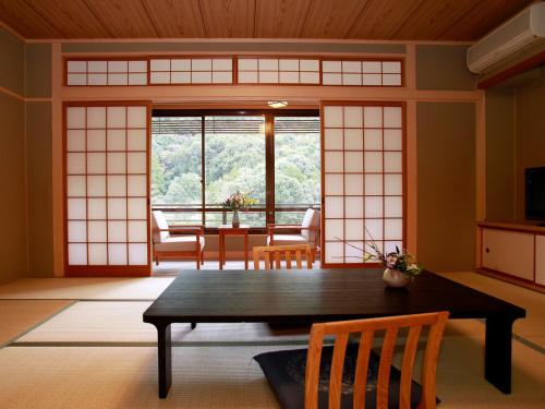 a room with a table and chairs and a window at Yumoto Kanko Hotel Saikyo in Nagato