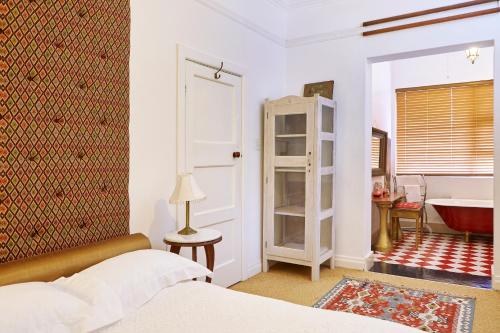 1 dormitorio con 1 cama y baño con lavamanos en Bella Ev Guest House, en Muizenberg