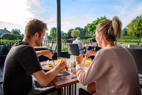 a man and woman sitting at a table eating food at Maashof in Venlo