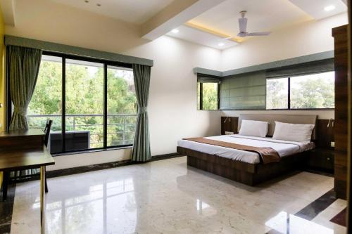 a bedroom with a bed and a desk and windows at Aquilla Villa in Lonavala