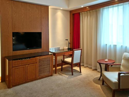 Pokój z telewizorem, biurkiem i pokojem w obiekcie Mason Hotel w Szanghaju