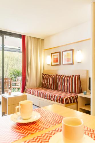 - un salon avec un canapé et deux tasses sur une table dans l'établissement Pierre & Vacances Le Moulin des Cordeliers, à Loches