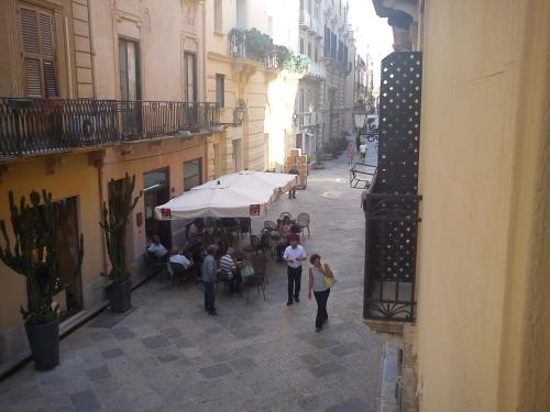 a group of people walking down a street with tables at Appartamenti "Elegante & Romantico" in Trapani