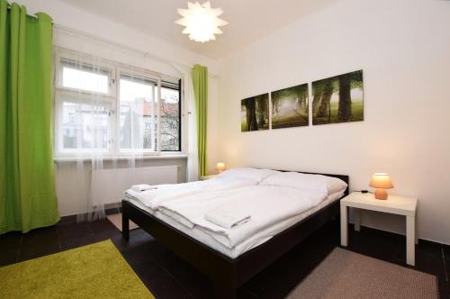 a bedroom with a bed and a window with green curtains at Císařka Apartment in Prague