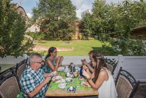 grupa ludzi siedzących przy stole jedzących w obiekcie Hotel & Auberge le Journal w mieście Sankt Wendel