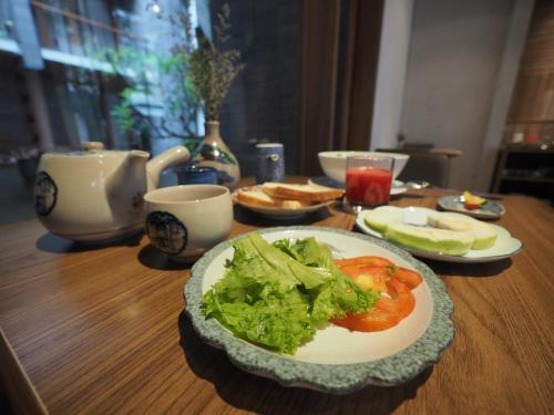 a wooden table with a plate of salad and tomatoes at Mai's Boutique in Da Nang