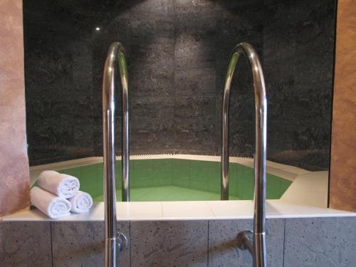 uma banheira com duas toalhas e duas torneiras em Wellness Hotel Jean De Carro em Karlovy Vary