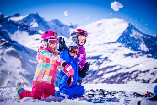 three children sitting in the snow on a mountain at Bergparadies - inklusive Eintritt in die Alpentherme in Dorfgastein