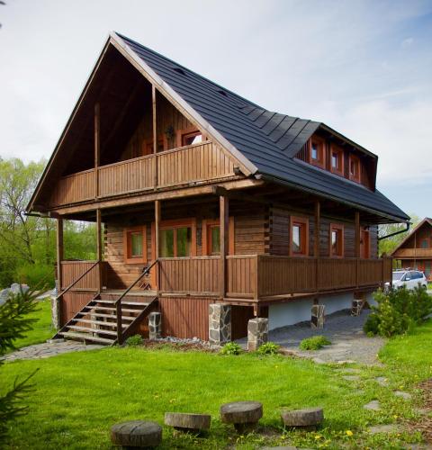 a large wooden house with a black roof at Chata Musica in Nižné Malatíny