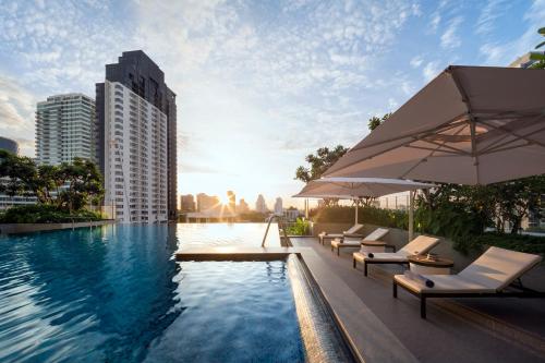 a pool with chairs and an umbrella and a building at Somerset Sukhumvit Thonglor Bangkok in Bangkok