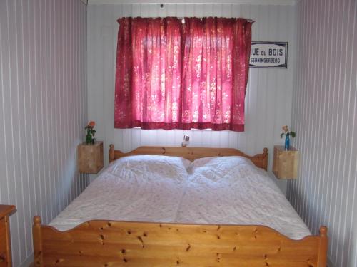 a bedroom with a wooden bed with a pink window at Tisvildehegn BandB in Helsinge