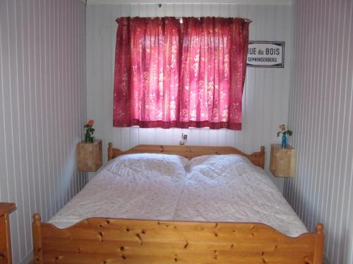 um quarto com uma cama de madeira e uma janela rosa em Tisvildehegn BandB em Helsinge