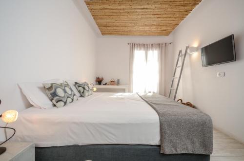 a white bedroom with a large bed and a flat screen tv at Thomais Studios in Naxos Chora
