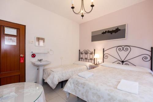 a bedroom with two beds and a sink and a mirror at Pension Mesones in Granada