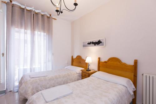 two beds in a white room with a window at Pension Mesones in Granada