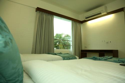 a hotel room with two beds and a window at Niko Hotels in Cochin