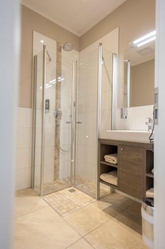 a bathroom with a shower and a sink at Ostseehotel Warnemünde in Warnemünde