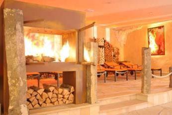 a living room with a fireplace and a table at Feuriger Tatzlwurm Berghotel & Spa, BW Signature Collection in Oberaudorf