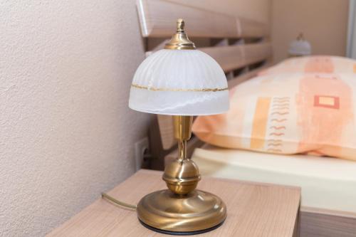 a brass lamp on a table next to a bed at Penzión Kastelán in Bojnice