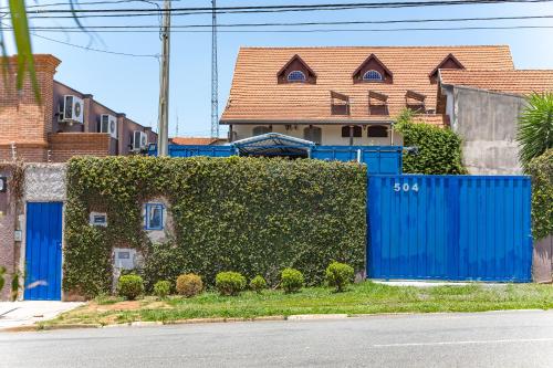 a blue fence in front of a house with a hedge at Residencial Villa Container in Campinas