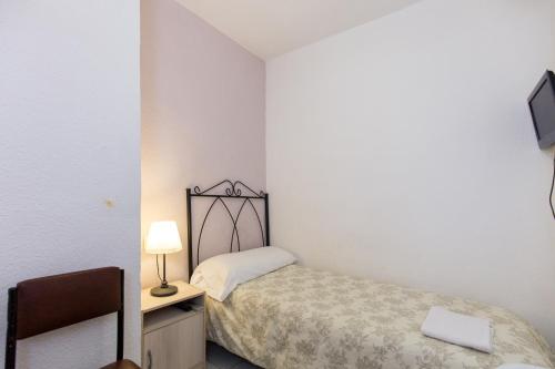 a small bedroom with a bed and a chair at Pension Mesones in Granada