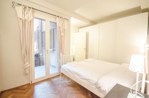 a white bedroom with a bed and a window at Azeglio apartment, a due passi da Piazza Maggiore in Bologna