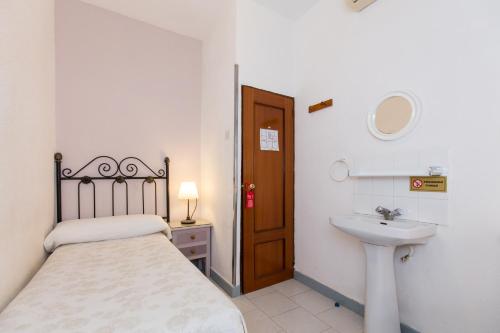 a small bedroom with a bed and a sink at Pension Mesones in Granada